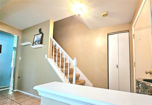 stairs featuring a textured ceiling and tile patterned flooring