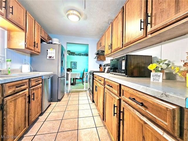 kitchen featuring a textured ceiling, light tile patterned floors, and stainless steel appliances