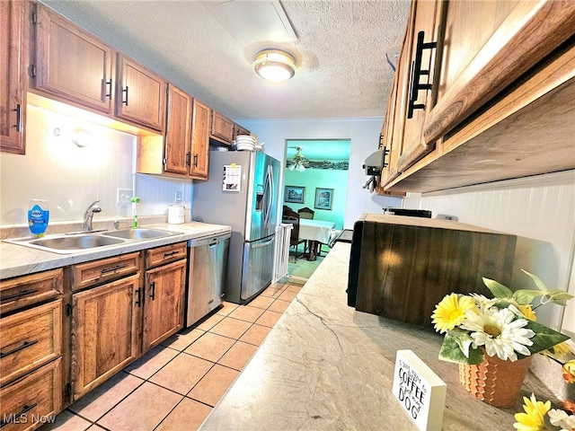 kitchen with light tile patterned flooring, appliances with stainless steel finishes, sink, and a textured ceiling