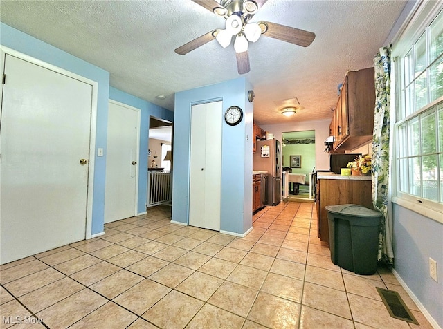 kitchen featuring a textured ceiling, ceiling fan, and light tile patterned floors