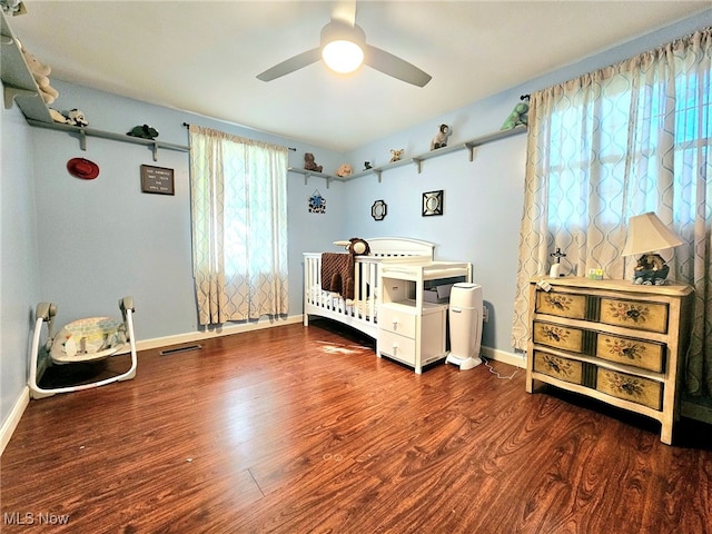 bedroom with ceiling fan, a crib, and hardwood / wood-style flooring