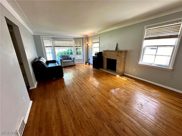 unfurnished living room featuring wood-type flooring, ornamental molding, and a premium fireplace