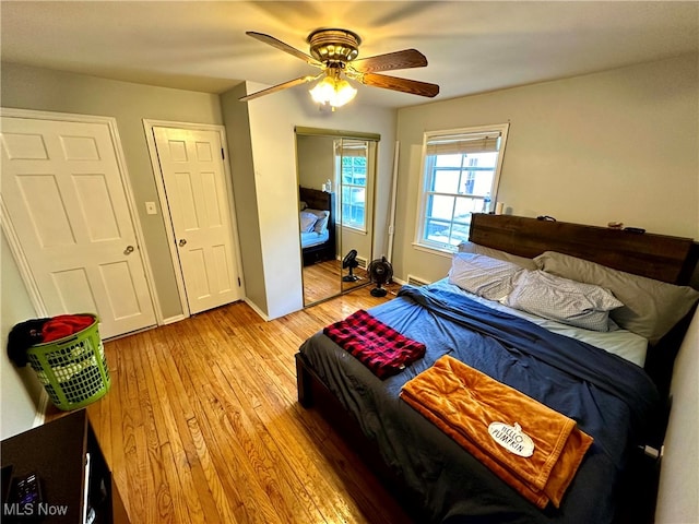 bedroom with ceiling fan, two closets, and light wood-type flooring