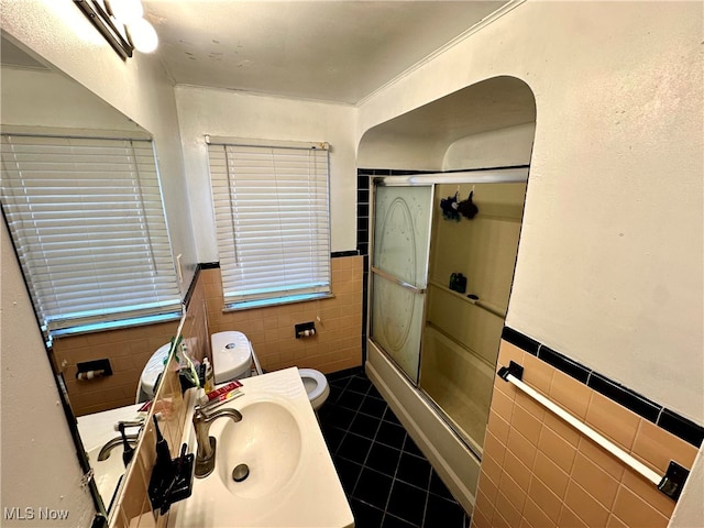 full bathroom with vanity, shower / bath combination with glass door, tile patterned floors, toilet, and tile walls