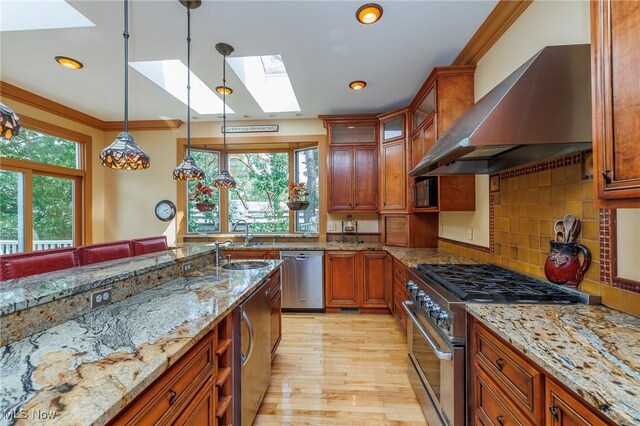 kitchen featuring stainless steel appliances, wall chimney exhaust hood, a skylight, and plenty of natural light