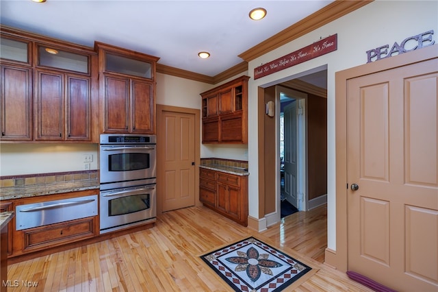 kitchen with light hardwood / wood-style flooring, ornamental molding, dark stone countertops, and double oven