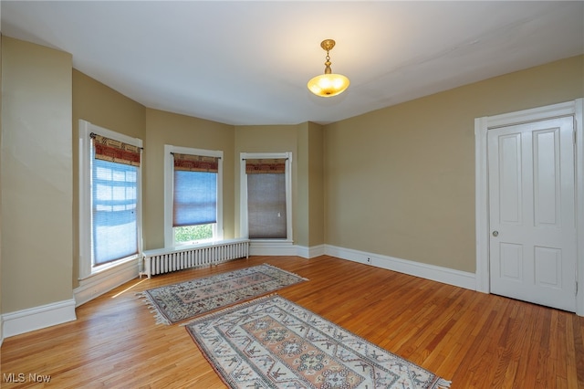 unfurnished room featuring light wood-type flooring and radiator heating unit