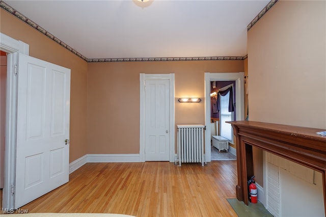 unfurnished bedroom with ensuite bath, light hardwood / wood-style flooring, and radiator heating unit