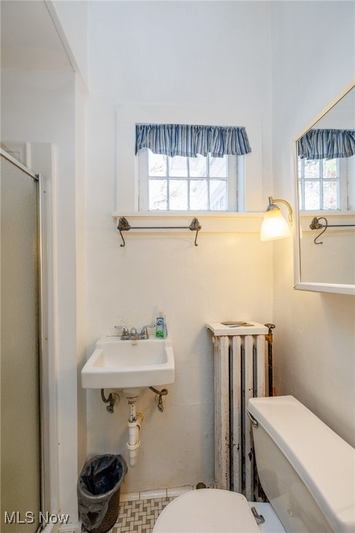 bathroom with tile patterned flooring, radiator heating unit, walk in shower, and toilet