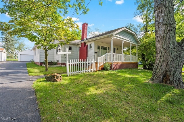 bungalow-style home featuring a garage, a front yard, a porch, and an outbuilding