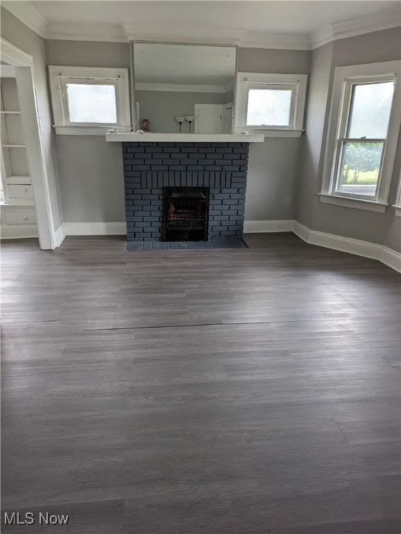 unfurnished living room featuring wood-type flooring, crown molding, and a brick fireplace