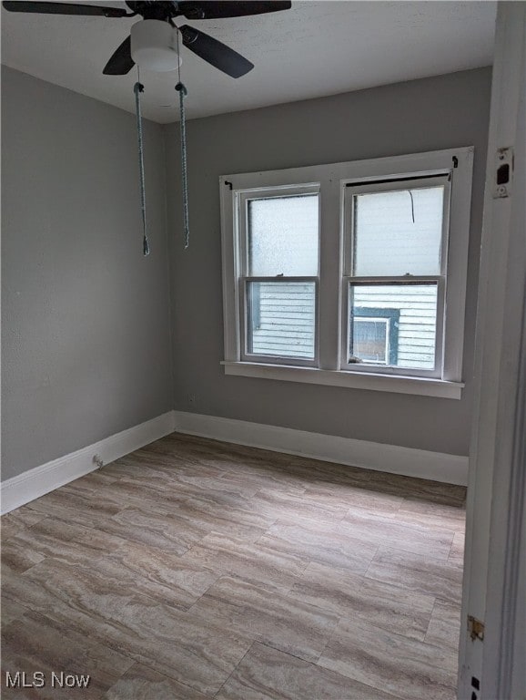 empty room with ceiling fan and light hardwood / wood-style flooring