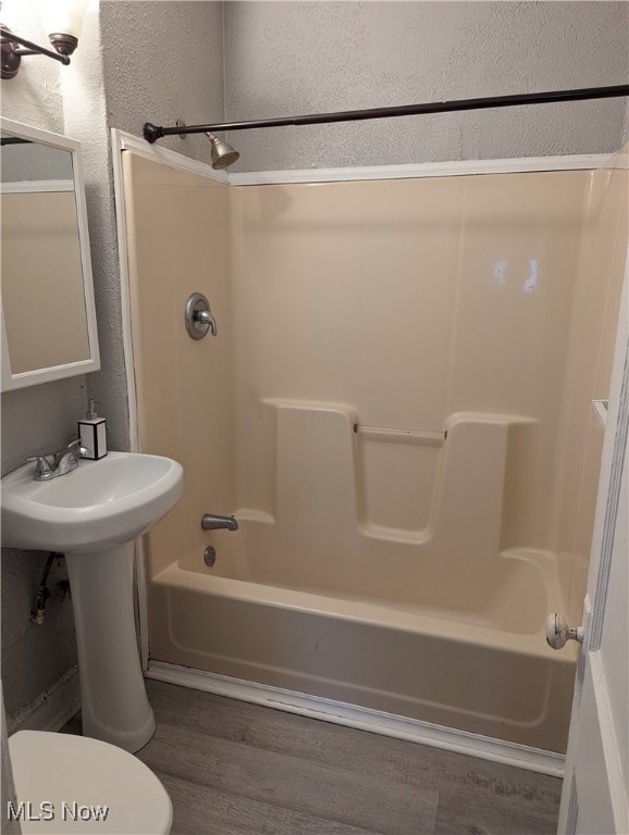 bathroom with  shower combination, hardwood / wood-style floors, and toilet