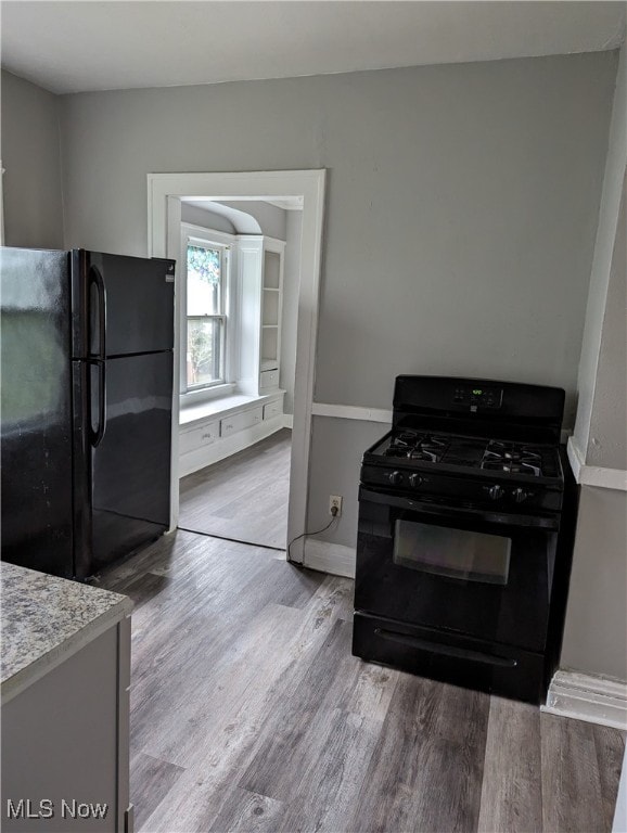 kitchen with light hardwood / wood-style floors and black appliances