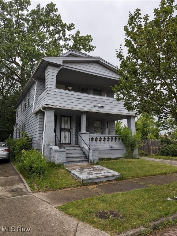 view of front of property with a balcony, a front lawn, and covered porch