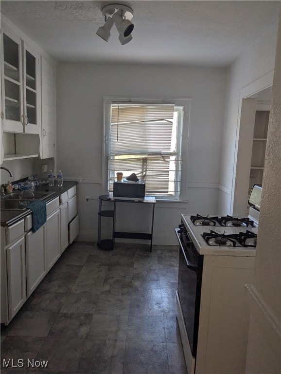 kitchen featuring white cabinets, white range with gas stovetop, and sink