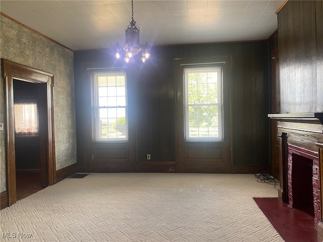 interior space featuring wood walls, a wealth of natural light, carpet, and a notable chandelier