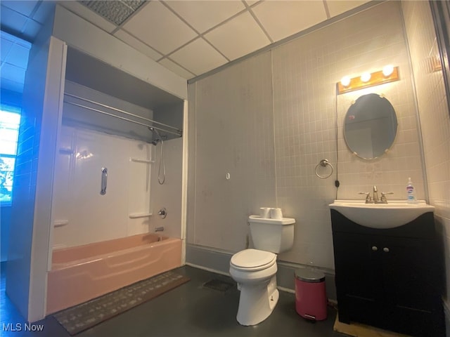 full bathroom featuring toilet, a drop ceiling, vanity, shower / bath combination, and tile walls