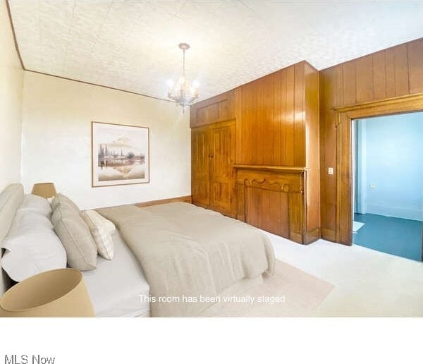 bedroom with an inviting chandelier, wooden walls, and carpet floors