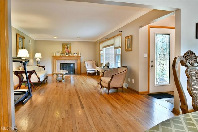 living room featuring ornamental molding, wood finished floors, a glass covered fireplace, and baseboards