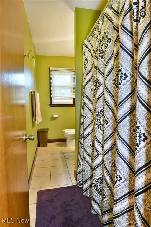 full bathroom featuring toilet, lofted ceiling, baseboards, and tile patterned floors