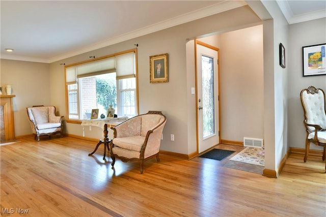 foyer entrance featuring baseboards, visible vents, crown molding, and light wood finished floors