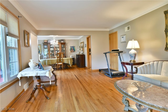 living room featuring light hardwood / wood-style flooring, crown molding, and a chandelier