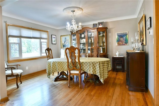 dining space featuring light wood-style floors, crown molding, baseboards, and an inviting chandelier