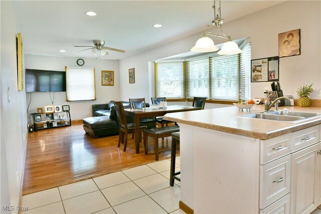 kitchen with sink, white cabinetry, ceiling fan, light tile patterned floors, and pendant lighting