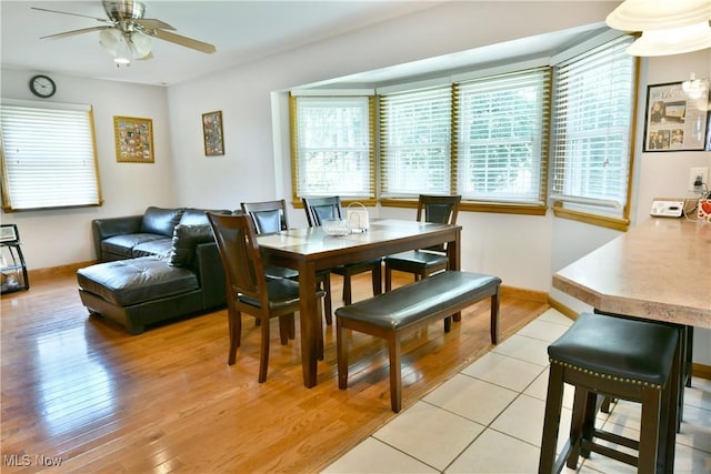 dining space with ceiling fan, light wood-style floors, baseboards, and a healthy amount of sunlight