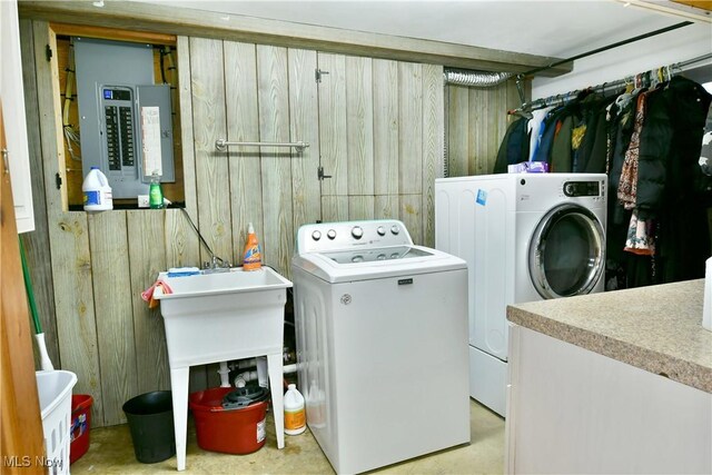 laundry room with wooden walls, washing machine and dryer, and electric panel