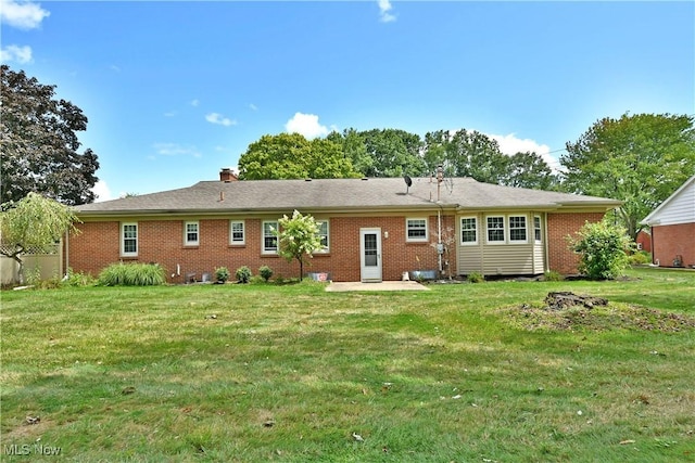 rear view of house with brick siding and a lawn