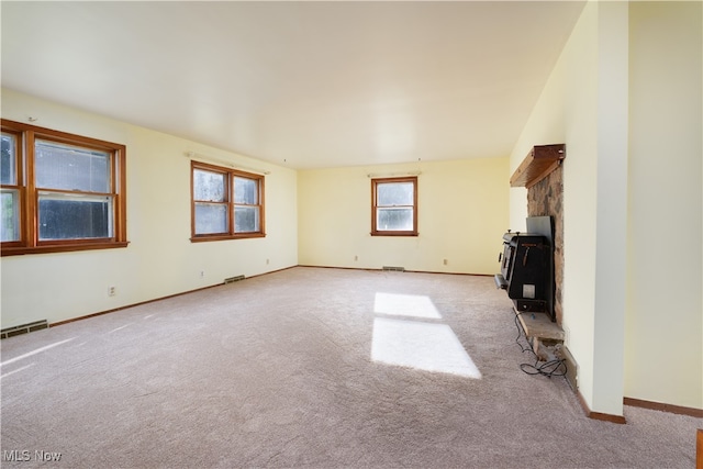 unfurnished living room featuring a fireplace, a healthy amount of sunlight, and light carpet