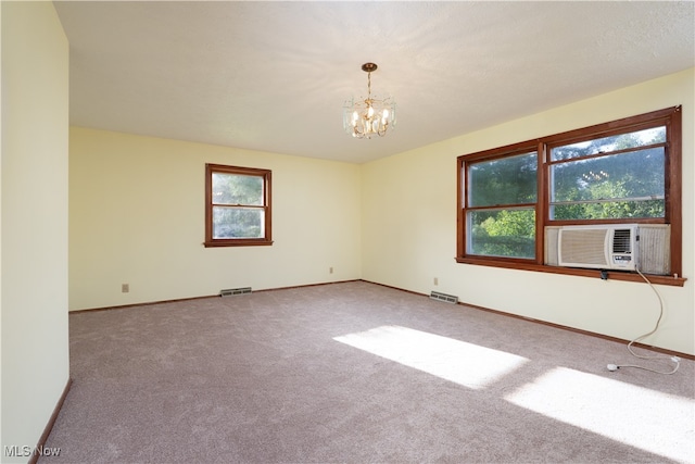 unfurnished room with carpet flooring, a notable chandelier, a healthy amount of sunlight, and cooling unit