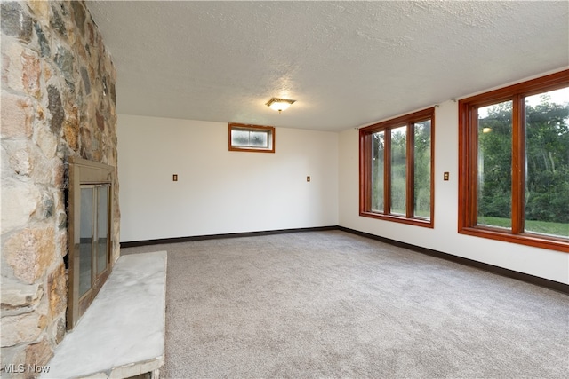 unfurnished living room with carpet floors, a textured ceiling, and a fireplace