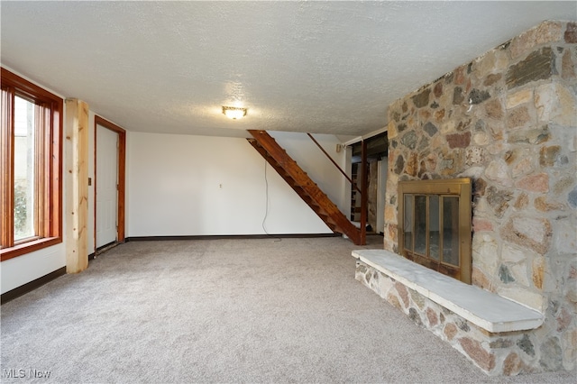 unfurnished living room featuring a fireplace, carpet, a textured ceiling, and a healthy amount of sunlight