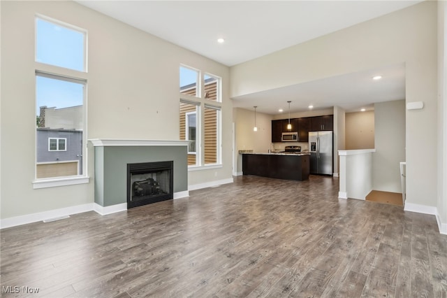 unfurnished living room with a towering ceiling and dark hardwood / wood-style floors