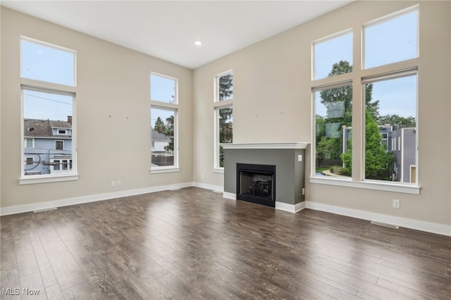 unfurnished living room featuring a wealth of natural light and dark hardwood / wood-style flooring