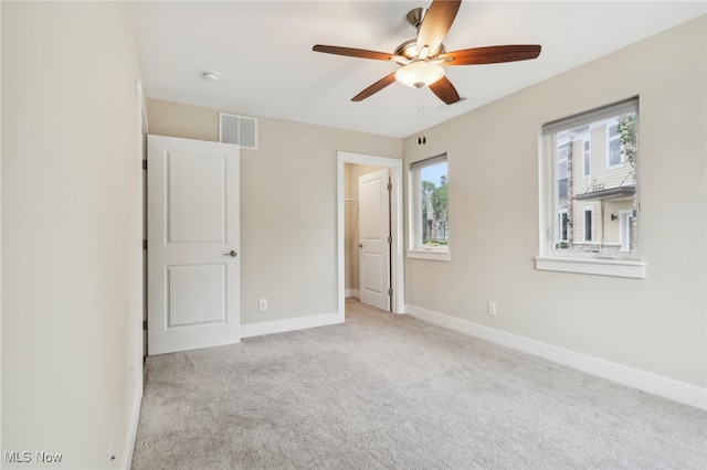 unfurnished bedroom with ceiling fan, multiple windows, and light carpet