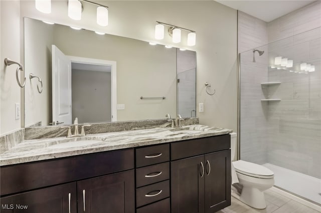 bathroom with tile patterned flooring, toilet, a tile shower, and vanity