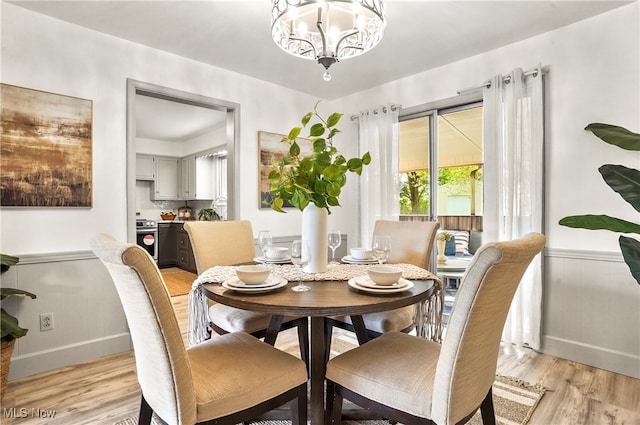 dining area with light hardwood / wood-style floors and a chandelier