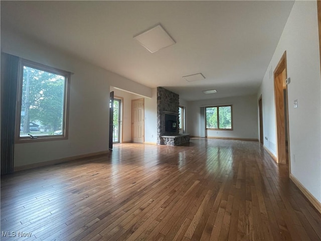 unfurnished living room featuring hardwood / wood-style floors and a stone fireplace