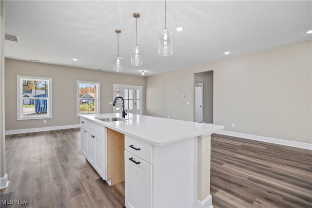 kitchen with sink, a center island with sink, decorative light fixtures, hardwood / wood-style floors, and white cabinetry