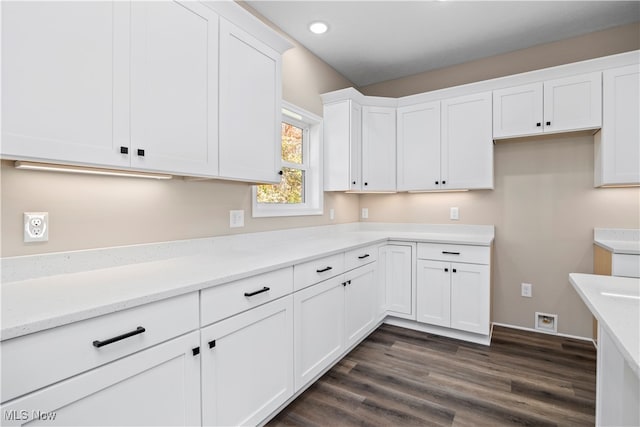 kitchen with white cabinetry, dark hardwood / wood-style floors, and light stone counters