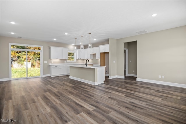 kitchen featuring a center island with sink, white cabinetry, dark wood-type flooring, and plenty of natural light