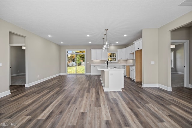 kitchen with dark hardwood / wood-style floors, hanging light fixtures, and an island with sink