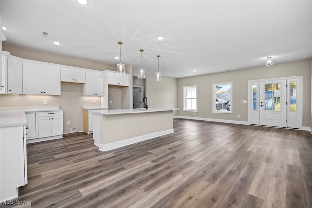 kitchen with white cabinetry, an island with sink, hanging light fixtures, and dark hardwood / wood-style flooring