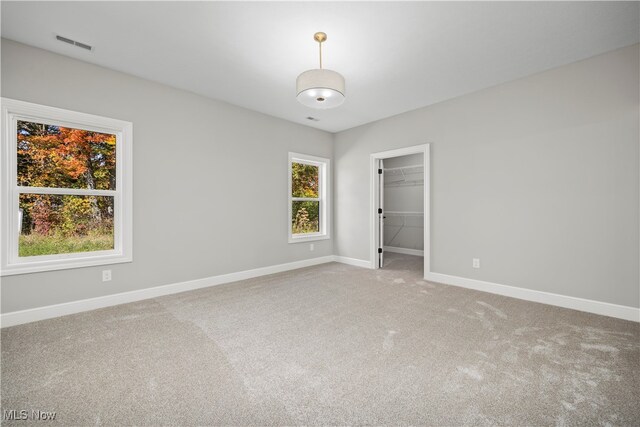 unfurnished bedroom featuring carpet, a walk in closet, and a closet