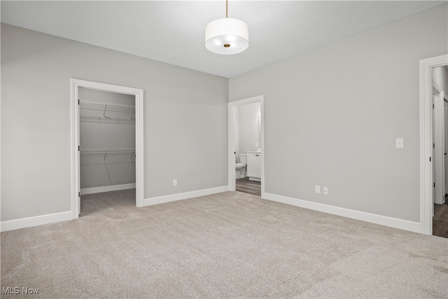 unfurnished bedroom with a walk in closet, carpet floors, and a closet