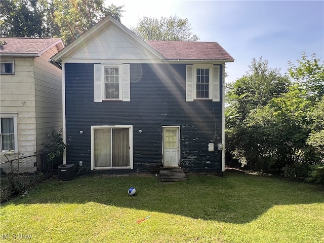 back of property featuring central AC unit and a yard